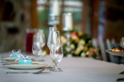 Festive table setting with decorated glasses and handmade gift boxes. Handmade gift box in plate and glasses on wedding table.