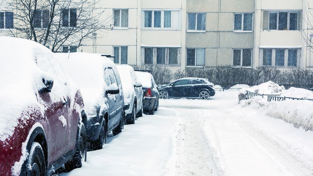 Snowfall in the city, cars overwhelmed with snow.