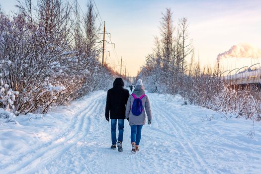 Young couple walking in the park in a winter sunny frosty day.