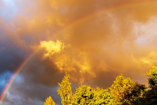 Rainbow after rain in a cloudy sky among dramatic clouds.