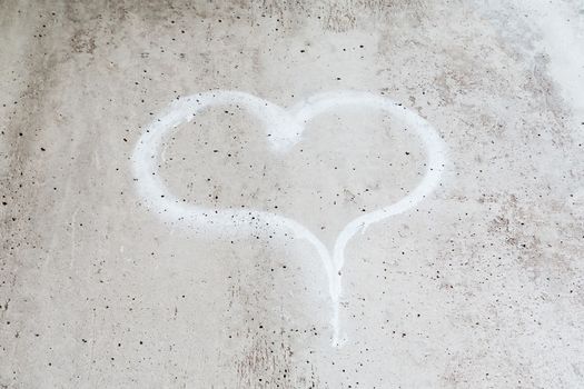 Heart drawn in chalk on a gray concrete wall.