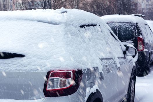 Snowfall in the city, cars overwhelmed with snow.