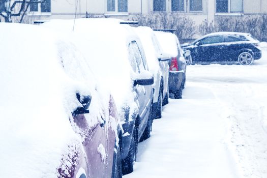 Snowfall in the city, cars overwhelmed with snow.