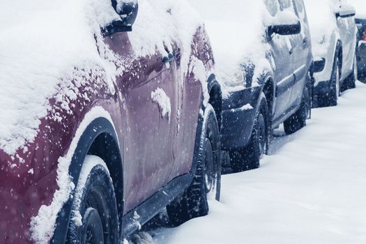 Snowfall in the city, cars overwhelmed with snow.