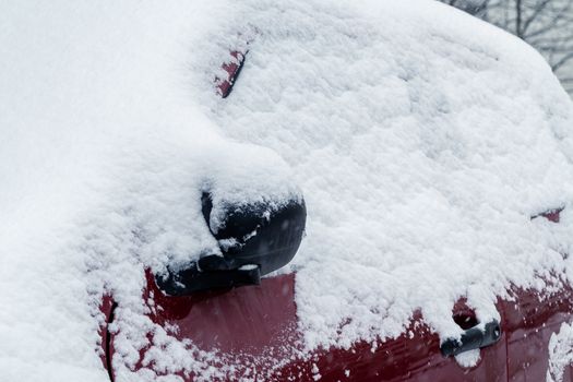 Snowfall in the city, part of the car covered by snow.