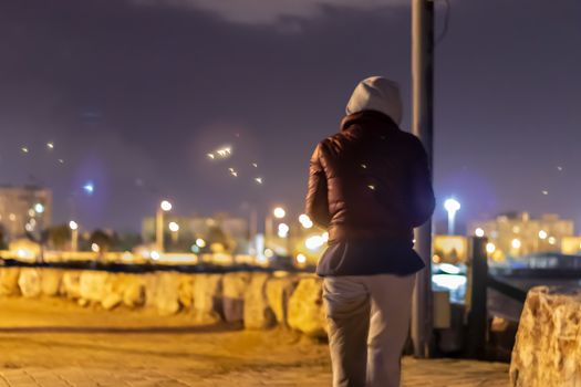 a girl walking at coast road at night under city lights. photo has taken at izmir/turkey.