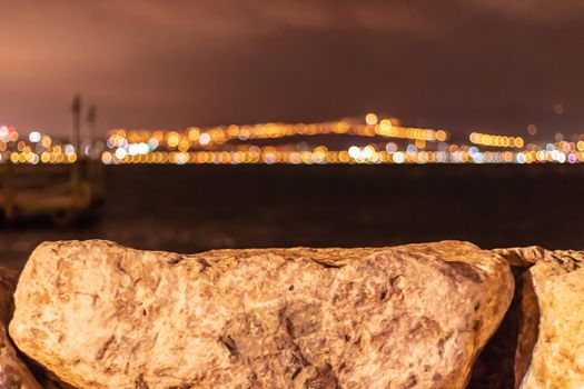 far city lights behind sea and focus on white rocks. photo has taken at izmir/turkey.