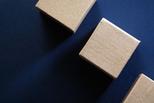 Three brown cardboard cube on dark blue background