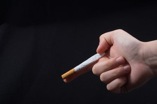 Hand  holding a cigarette like gun on black background