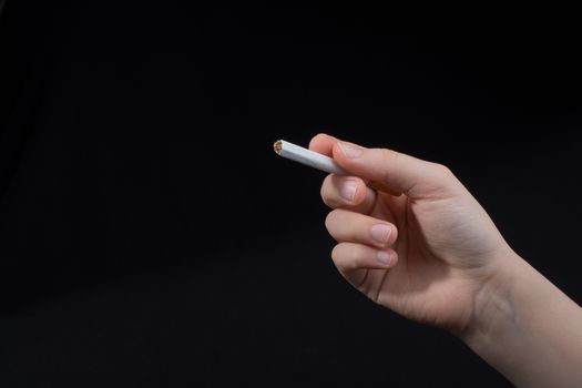 Hand is holding a cigarette on black background