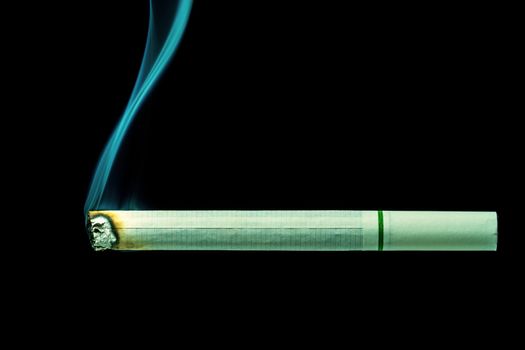 White cigarette is burn on black background. The concept of campaign to stop smoking.