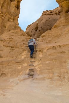 woman climbs a ladder at the arches rock in timna national park in south israel near Eilta