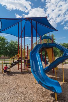 Kid playing at colorful playground near community recreation facility in Texas, America