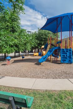 Back view of bench and colorful playground near community recreation facility in Texas, America