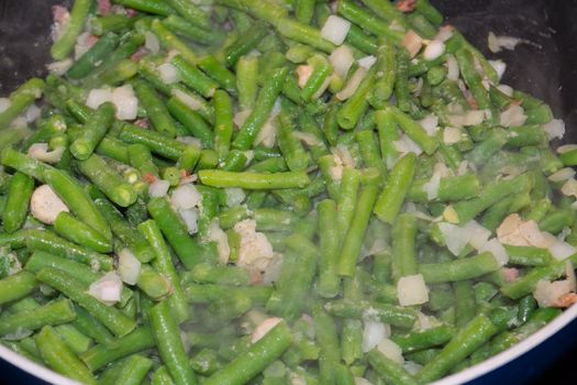 Steamed young green beans, vegetables and broccoli cooking in a pan.