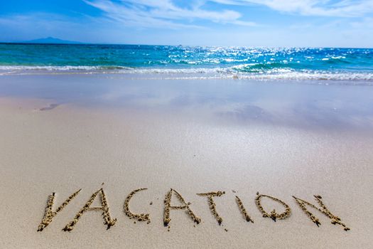 Vacation word writing on tropical sea beach