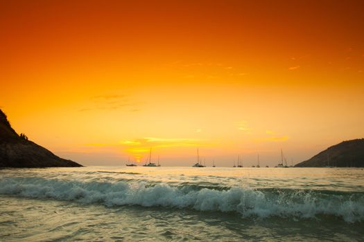 Sunset and dawn at sea against a backdrop of mountains and boats
