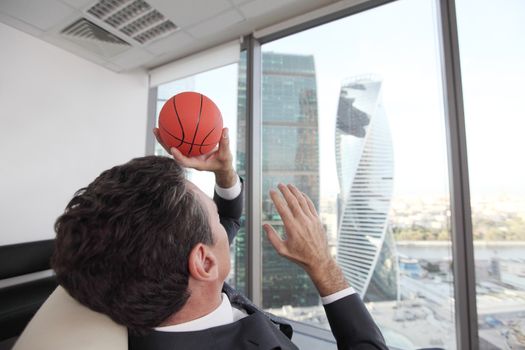 Business man playing with a basketball at the office