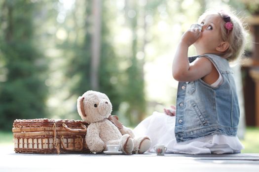 Pretty girl playing with teddy bear outdoors