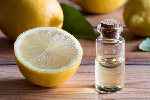 A bottle of lemon essential oil on a wooden table, with lemons in the background