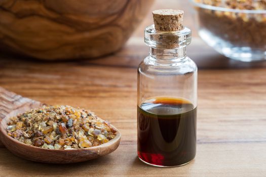 A bottle of myrrh essential oil with myrrh resin on a wooden table