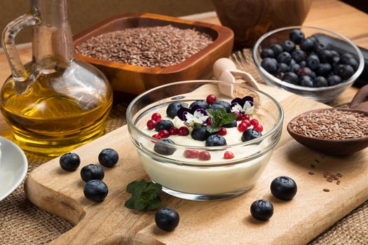 Cottage cheese blended with flax seed oil, topped with fresh blueberries and frozen wild cranberries, with flax seeds in the background