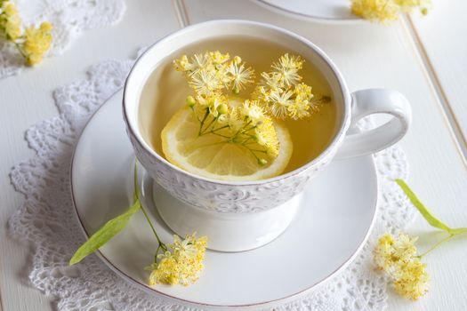 A cup of herbal tea with fresh linden flowers and lemon