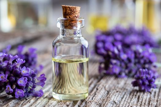 A bottle of essential oil with fresh lavender flowers on a rustic wooden background