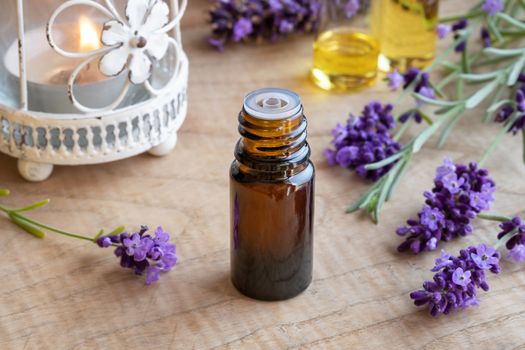 A bottle of essential oil with fresh blooming lavender twigs