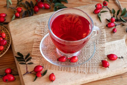 A cup of rose hip tea with fresh berries and leaves