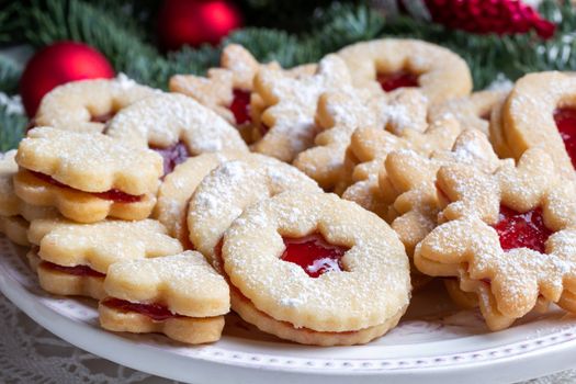 Traditional Linzer Christmas cookies filled with strawberry jam arranged on a plate 
