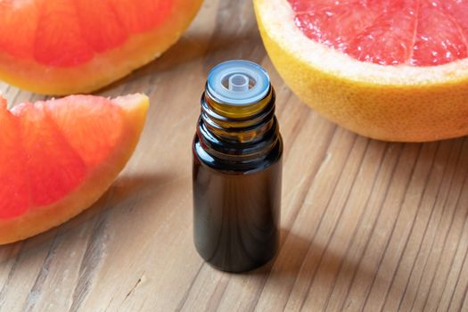 A bottle of essential oil with fresh pink grapefruit