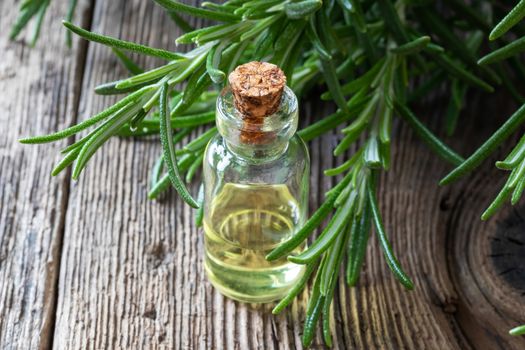 A transparent bottle of essential oil with fresh rosemary twigs