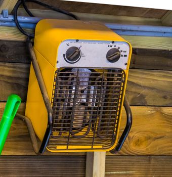 Simple electric heater hanging on a wooden wall, heating solutions