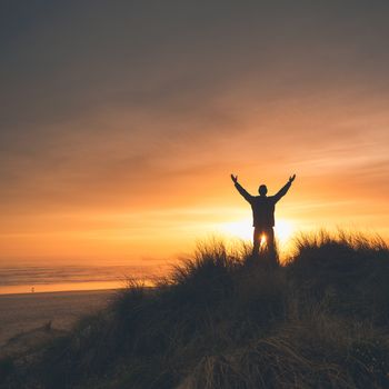 Man on the sand dunes at the sunset