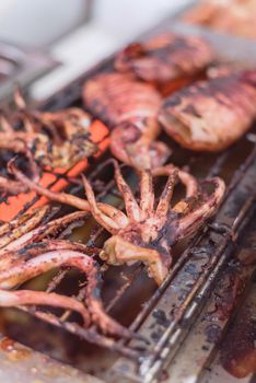 Grilled fresh squid on flaming in seafood, tasty squid grilled on street food BBQ stand.
