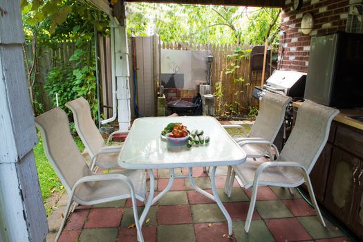 A rustic patio awaiting guests a white table with fresh vegetables and four chairs