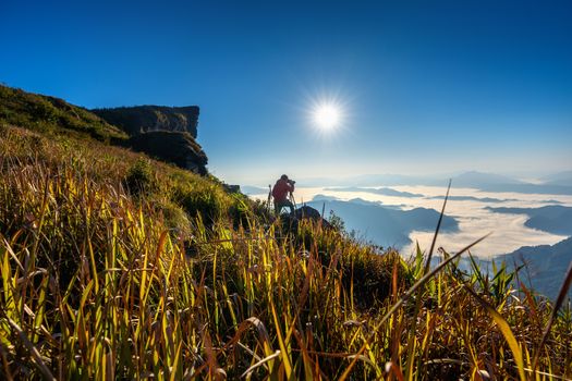 Photographer hand holding camera and standing on top of the rock in nature. Phu chi fa mountains in Chiang rai, Thailand