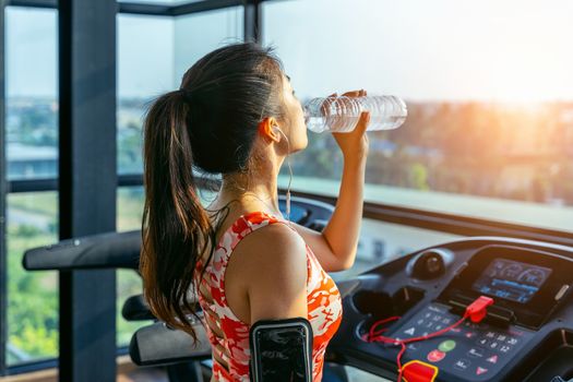 Young woman drinking water in the gym. Exercise concept.