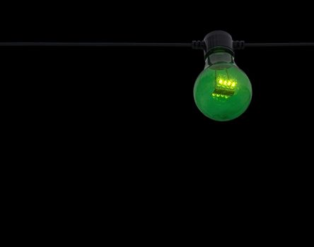 Green color lightbulb on string isolated on black