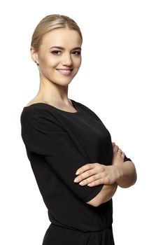 Portrait of smiling young attractive woman in black dress stands with crossed hands. Isolated at white background.
