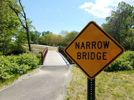 yellow narrow bridge sign with bridge or path or trail and trees