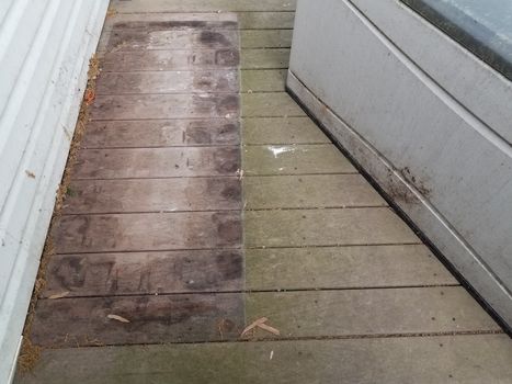 discolored or worn or weathered brown wood deck boards with algae and storage box