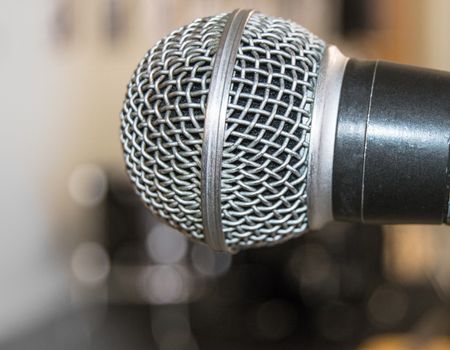 Microphone close-up, used by speaker to speak in conference room, seminar, University, lectures, blurred background.