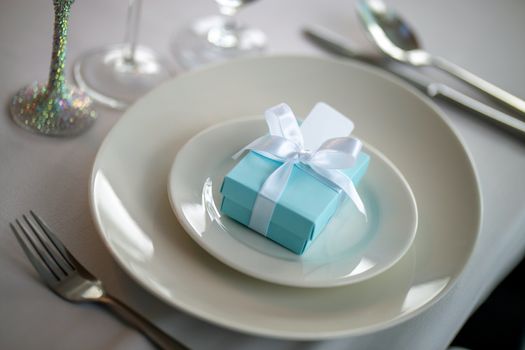 Festive table setting with handmade gift box on plate. Light blue handmade gift box in plate and fork on wedding table.