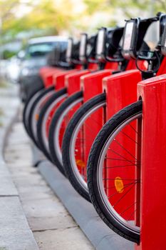 Many bicycle in a row. Red bicycles stand on a parking for rent. Eco friendly transportation concept.