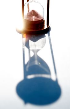 Play of shadows. Vintage hourglass with flowing sand against sunlight
