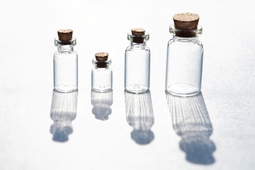 Set of small bottles with long shadow on white background