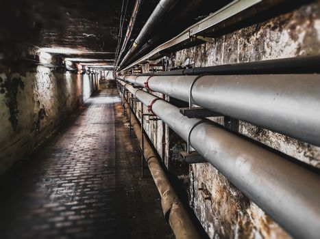 pipes on underground maintenance tunnel wall .