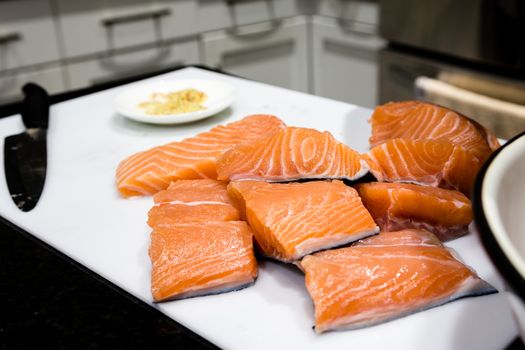 The cook pours spices into fish before putting them in the oven.